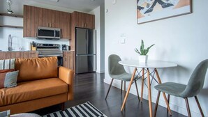Cozinha moderna com micro-ondas, forno e frigorífico. Possui área de jantar com mesa e cadeiras.