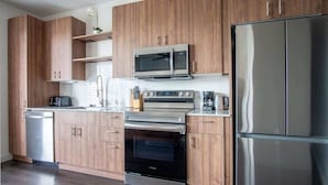 Uma cozinha moderna com armários de madeira, geladeira de aço inoxidável, micro-ondas, forno e lava-louças.