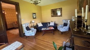A living room with patterned armchairs, a sofa, a wooden coffee table, and a chandelier. - Beautiful King Size Bed, private bath and breakfast included (Canandaigua)