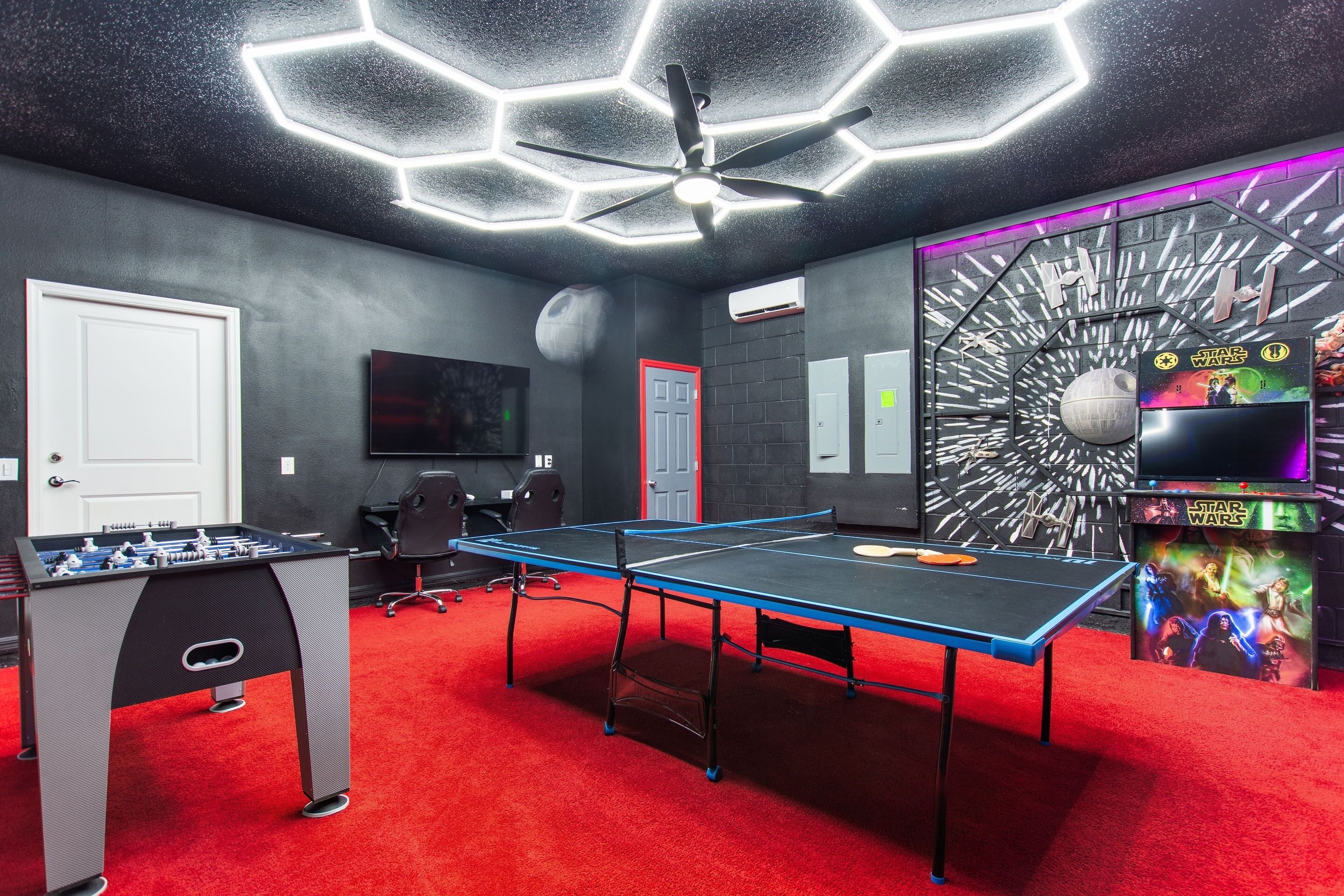 Une pièce équipée d’un baby-foot, d’une table de ping-pong et d’une décoration murale sur le thème de Star Wars.