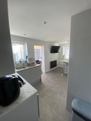 A modern kitchen with a built-in oven, a sink, and a window. - Prestatyn 2-bed Bungalow, Sleeps 5 With Hot Tub (Prestatyn)