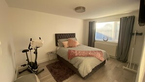 Un dormitorio con cama, bicicleta estática y ventana con cortinas.