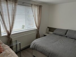 Una camera da letto con un letto, un comodino, un termosifone e una finestra con tende.