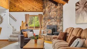 Un salón acogedor con chimenea de piedra, un sofá y una mesa de centro de madera.