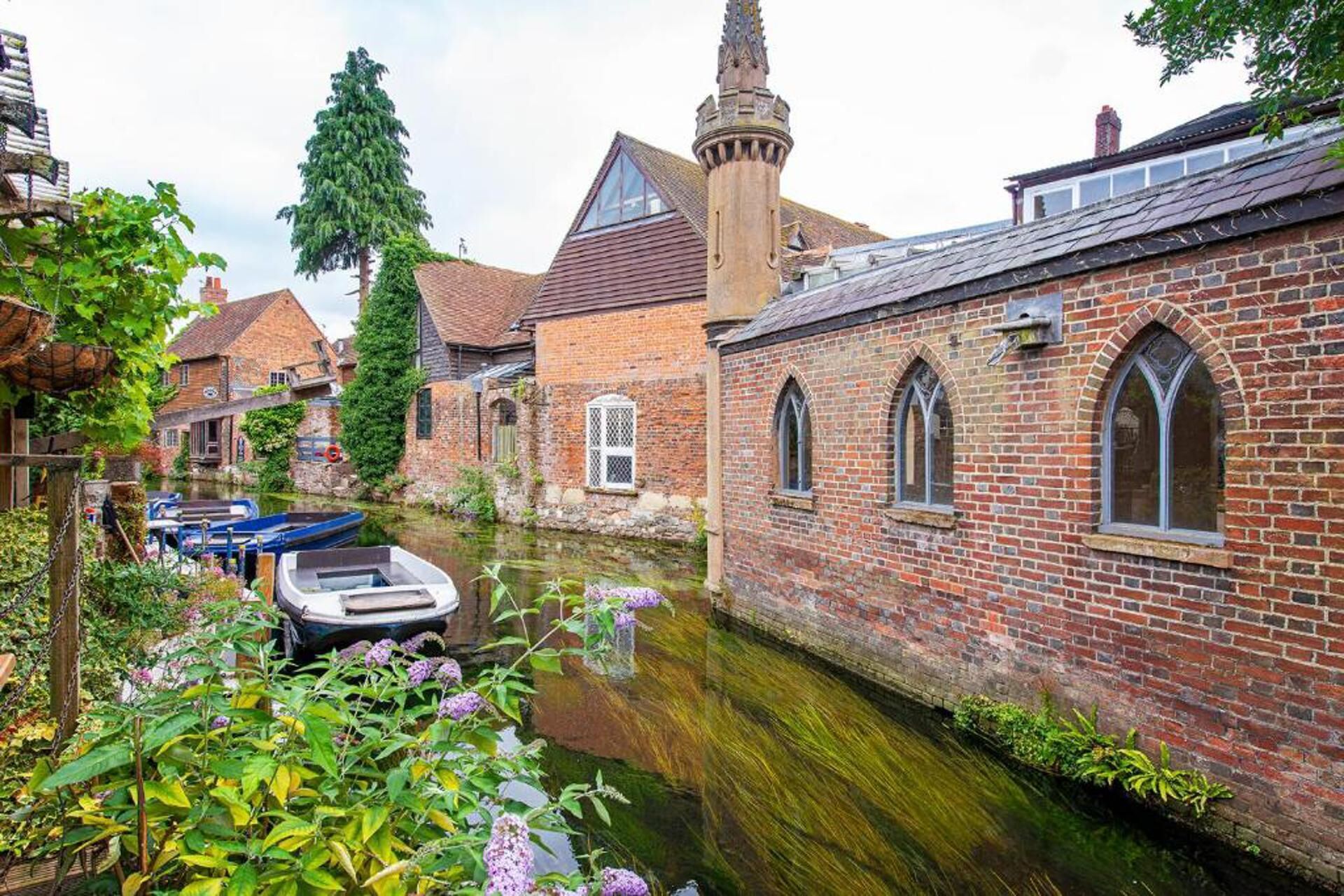 Ein Gebäude an einem Kanal, mit Backsteinfassade, Rundbogenfenstern und einem Turm.