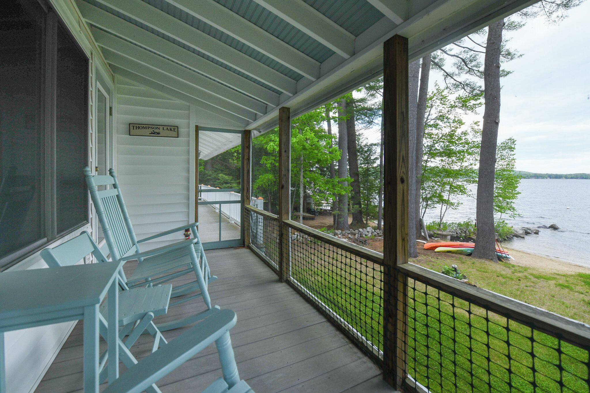 Une véranda couverte offrant une vue sur le lac Thompson, avec une balustrade en bois et une pancarte indiquant le nom du lac.