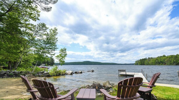 Udsigt over en sø med Adirondack-stole og et picnicbord.
