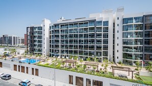 Et moderne hotel med pool, udendørs siddepladser og en tagterrasse.