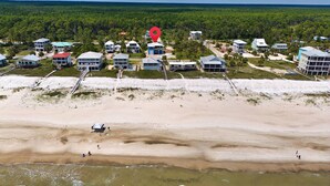 Een kustresort met strandvilla's, een zandstrand en een bebost achtergrond.