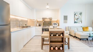 A modern kitchen with white cabinetry, a stainless steel refrigerator, and a central island with stools.