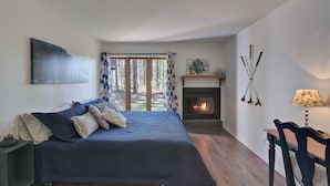 A bedroom with a bed, a fireplace, a desk, and a view of the outdoors. - Red pine sanctuary with A/C (Mont-Tremblant)