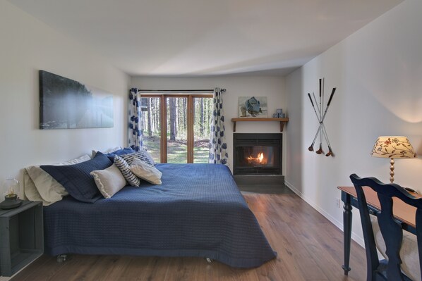 A bedroom with a bed, a fireplace, a desk, and a view of the outdoors. - Red pine sanctuary with A/C (Mont-Tremblant)
