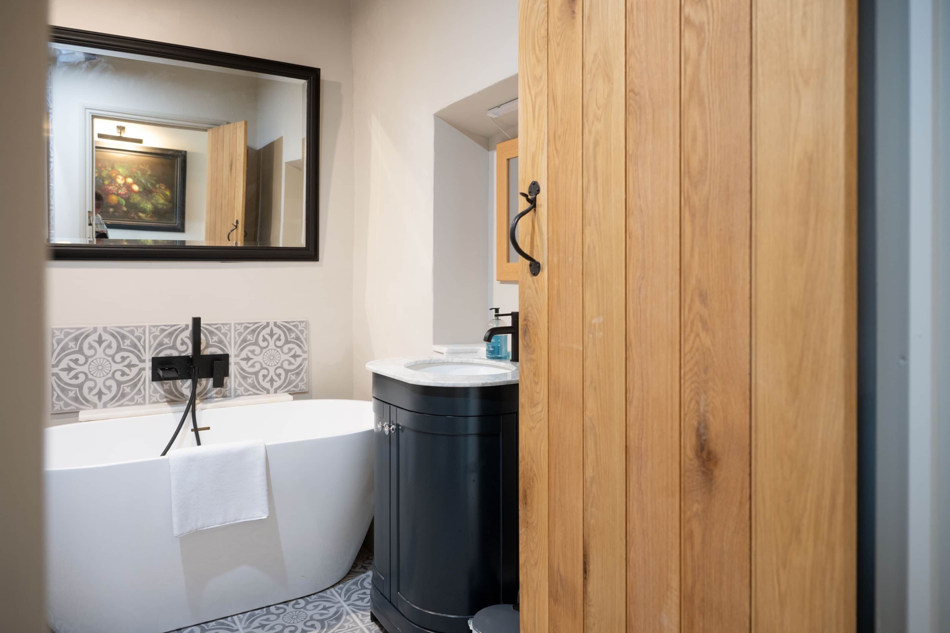 Une salle de bain moderne avec une baignoire sur pieds, un meuble-lavabo en bois et un grand miroir.