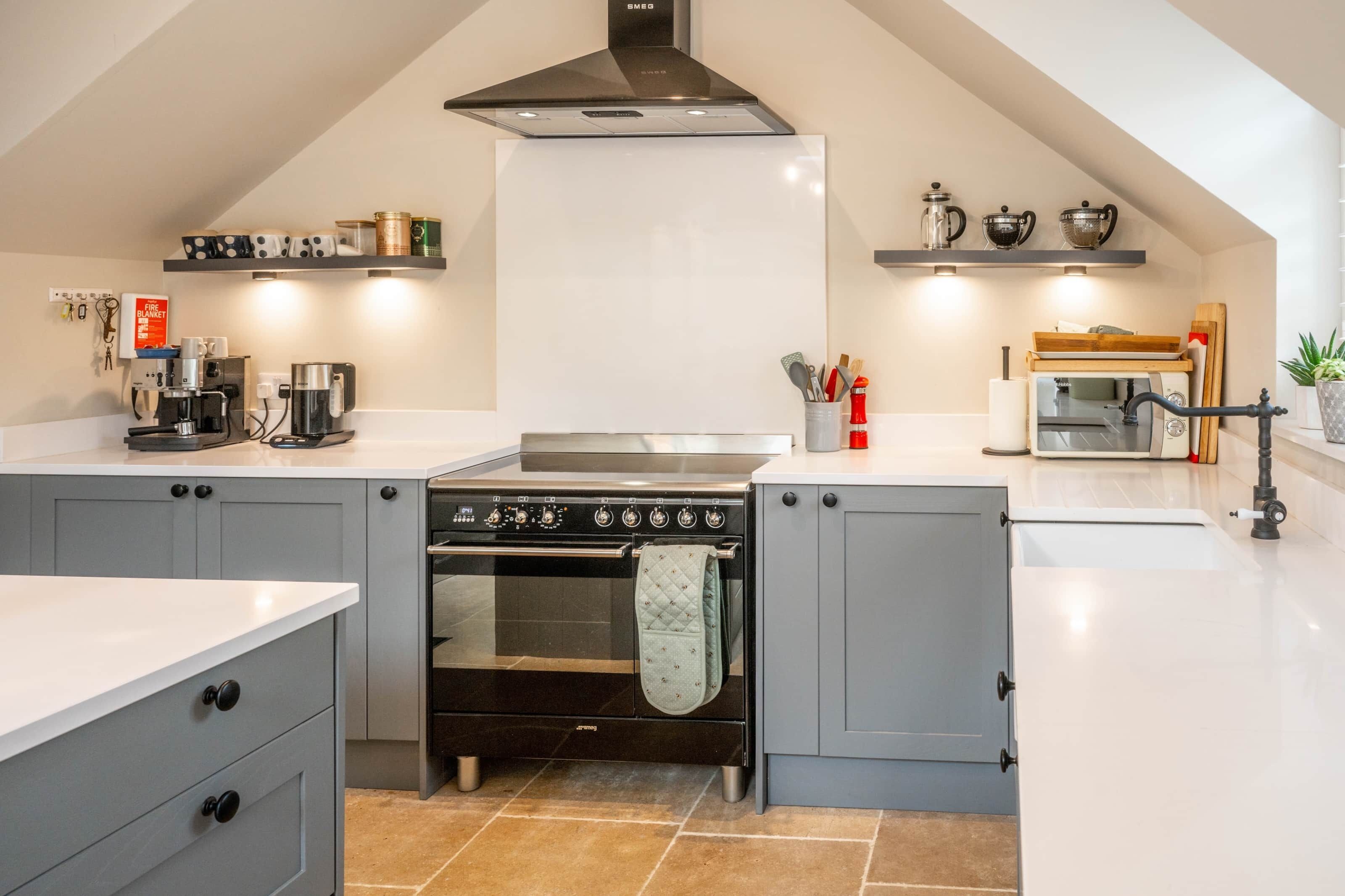 A modern kitchen with grey cabinets, a black stove, and a white countertop.