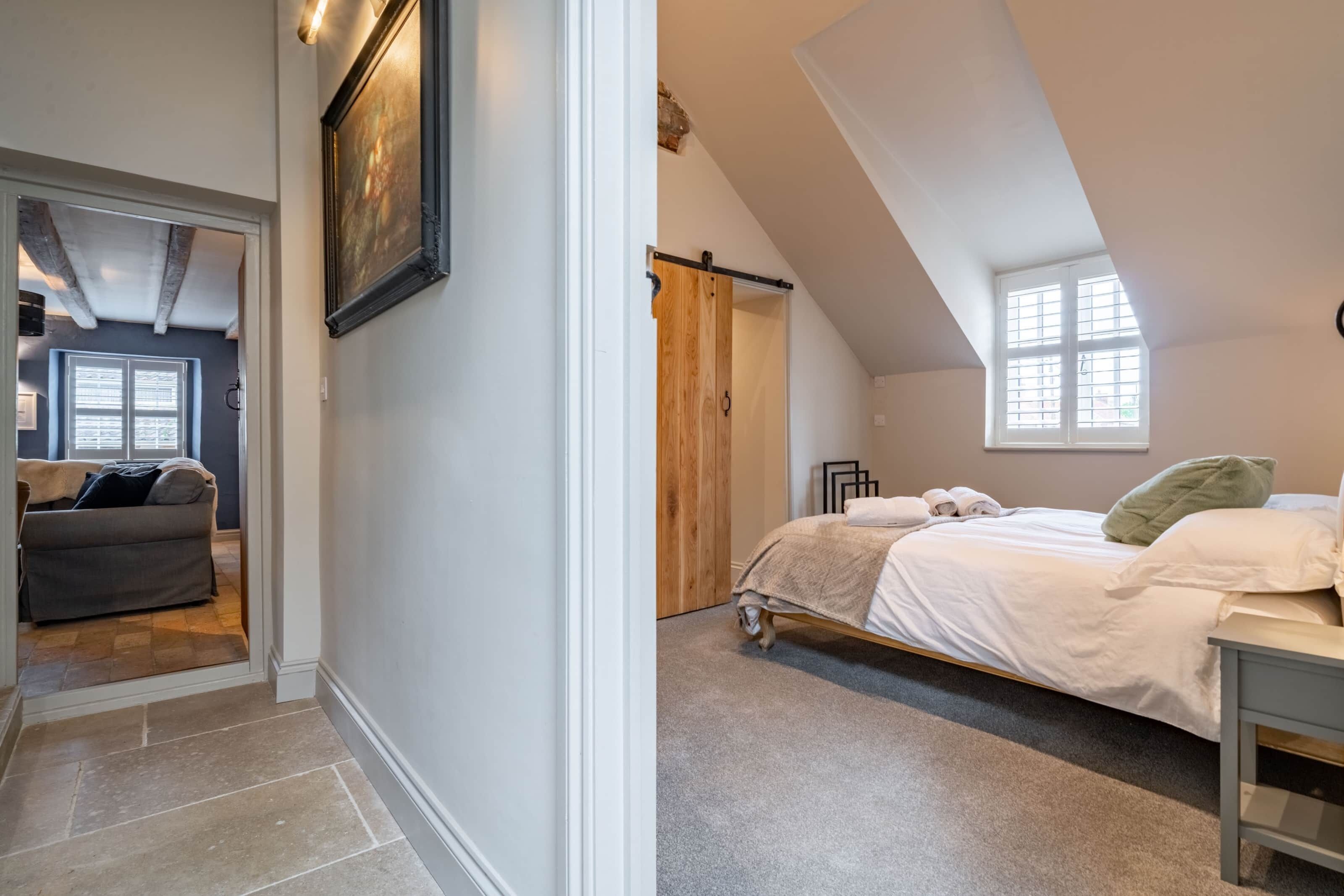 Un dormitorio con cama, mesita de noche y ventana.