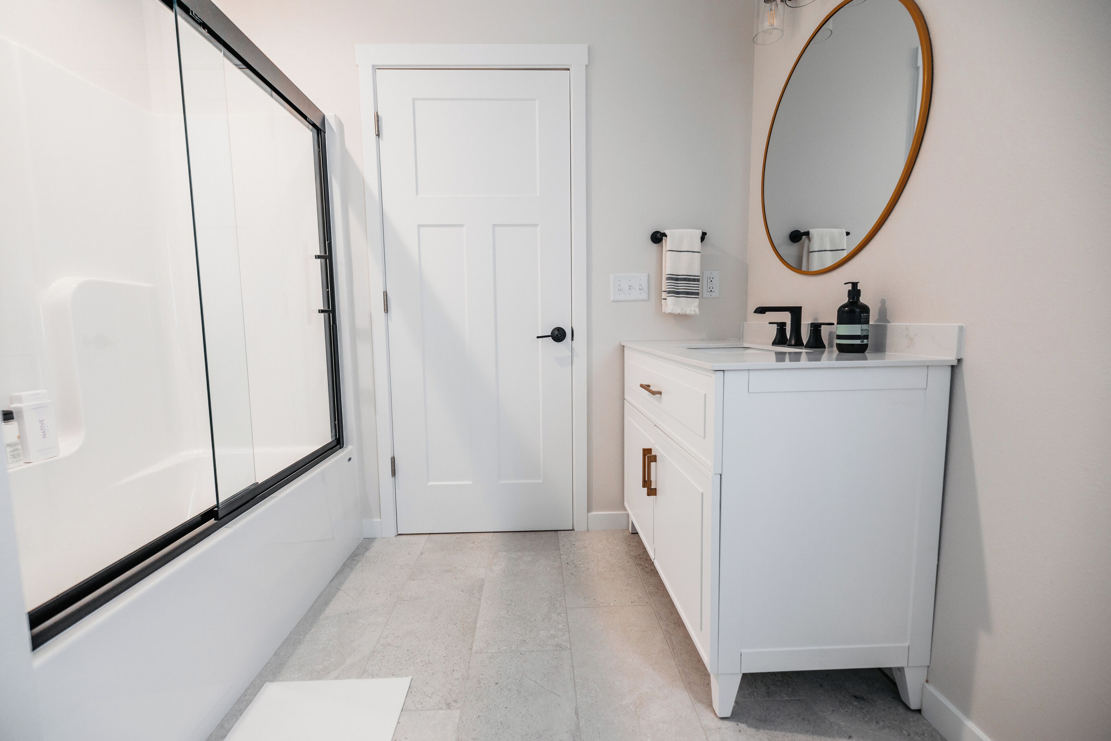 Une salle de bain avec un meuble-lavabo blanc, un miroir et une porte.