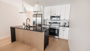 A modern kitchen with a central island, stainless steel appliances, and white cabinetry. - -The Cotton House- Modern, Clean, Close to MSU! (Mankato)