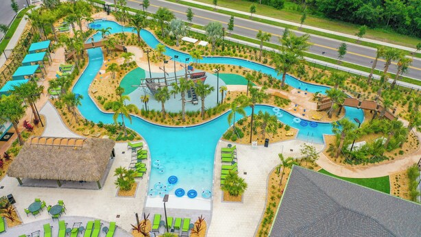 Ein Resort mit einem gewundenen Pool, Liegebereichen und einem Gebäude mit einem Reetdach.