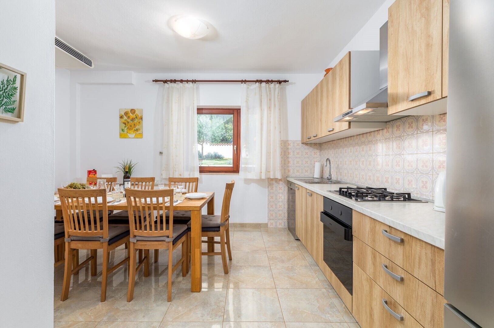 Una cocina moderna con armarios de madera, una estufa a gas y un comedor con mesa y sillas.