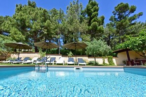 A swimming pool with lounge chairs and umbrellas, surrounded by trees. - House Max - charming holiday house with private pool, near the beach (Mugeba)