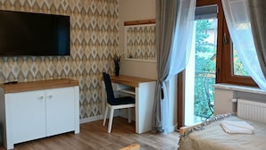 A bedroom with a bed, a desk, a chair, a TV, and a window with curtains. - Cozy 3-Bedroom Apartment for 5-6 guests with mountain views, with free parking (Zakopane)