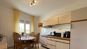 A compact kitchen with a dining table, chairs, a microwave, a coffee maker, and a window with curtains. - 5 Minuten von Koblenz Uni Entfernt Ferienwohnung (Koblenz)
