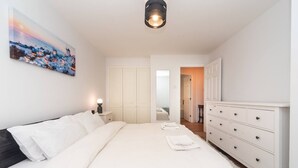 Une chambre à coucher avec un grand lit, une table de chevet, une commode et un tableau au mur.