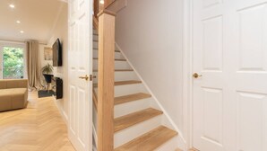 Un intérieur moderne avec un escalier en bois, des portes blanches et un canapé beige dans une pièce bien éclairée.
