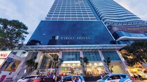 The exterior of the Virgo Hotel with a modern glass facade, a prominent entrance, and a visible flag. - S Lux Apartment Virgo Nha Trang (Nha Trang)