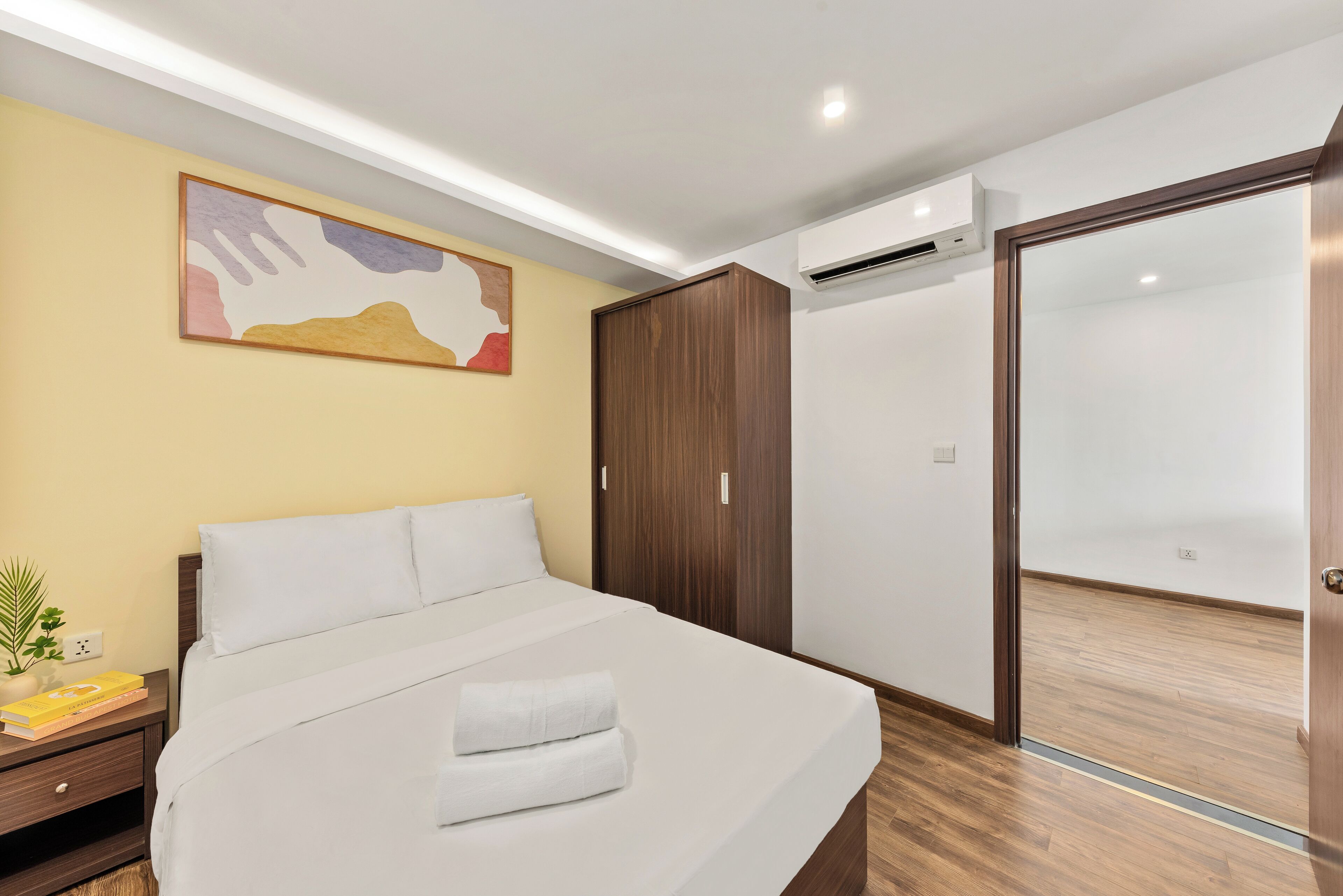 Un dormitorio ordenado con cama, armario y equipo de aire acondicionado.