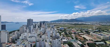 A cityscape with high-rise buildings, a body of water, and mountains in the background.
