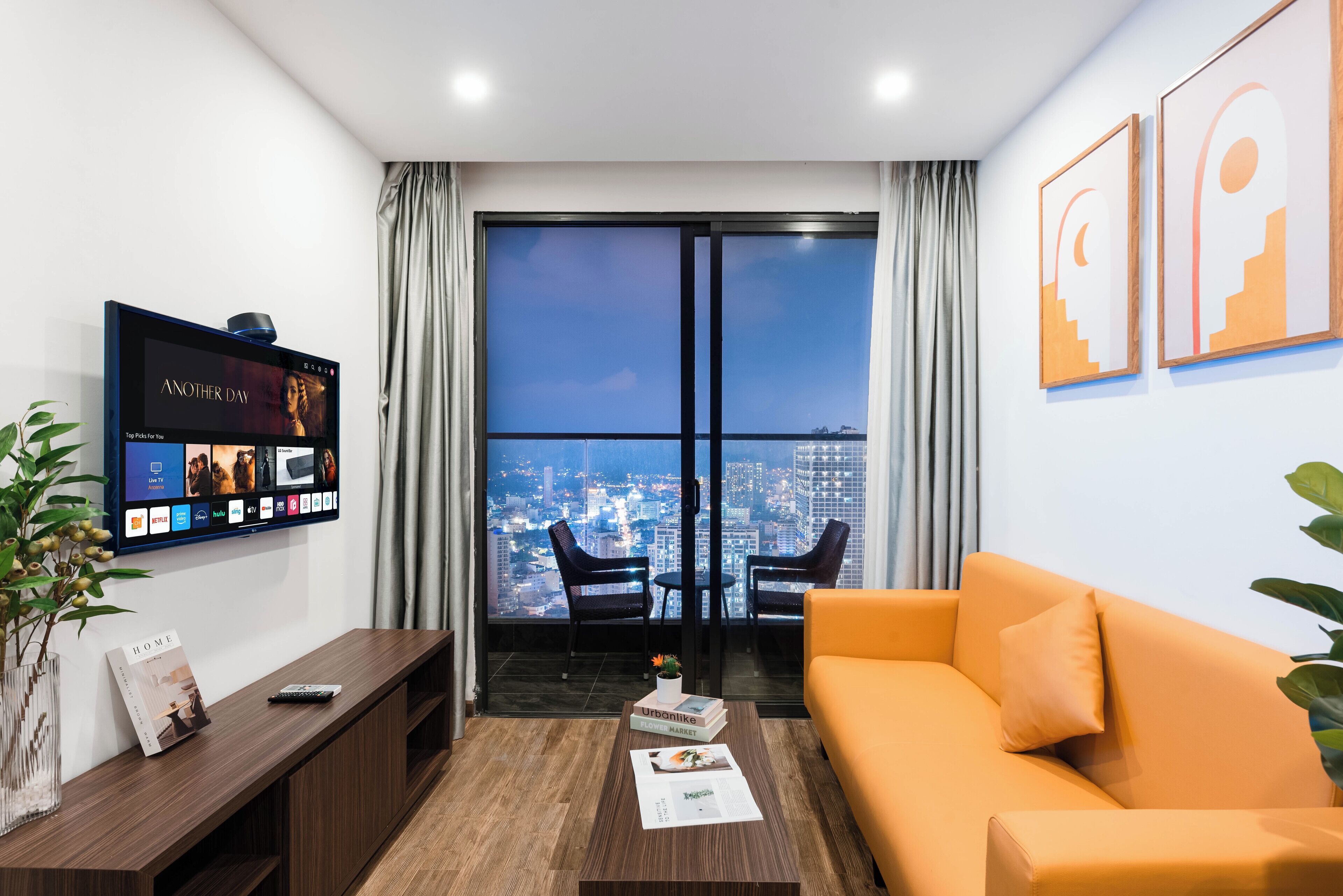 Una sala de estar moderna con un ventanal grande, un televisor de pantalla plana, un sofá, una mesa de centro y una estantería.