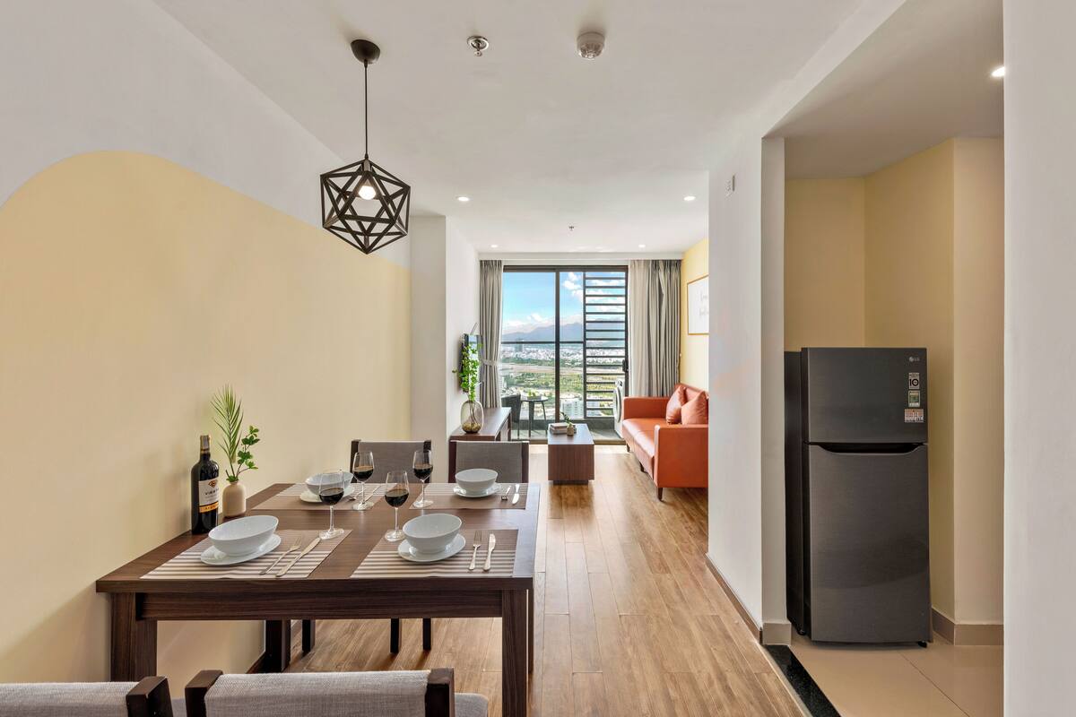 Un salon moderne avec un coin repas, un réfrigérateur noir et une vue sur la ville.