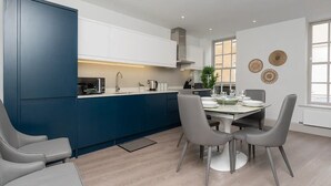 A modern kitchen with a central island, white cabinets, and a dining area with a table and chairs. - Stylish 2-bed apartment in the heart of Bath - Pass the Keys (Bath)