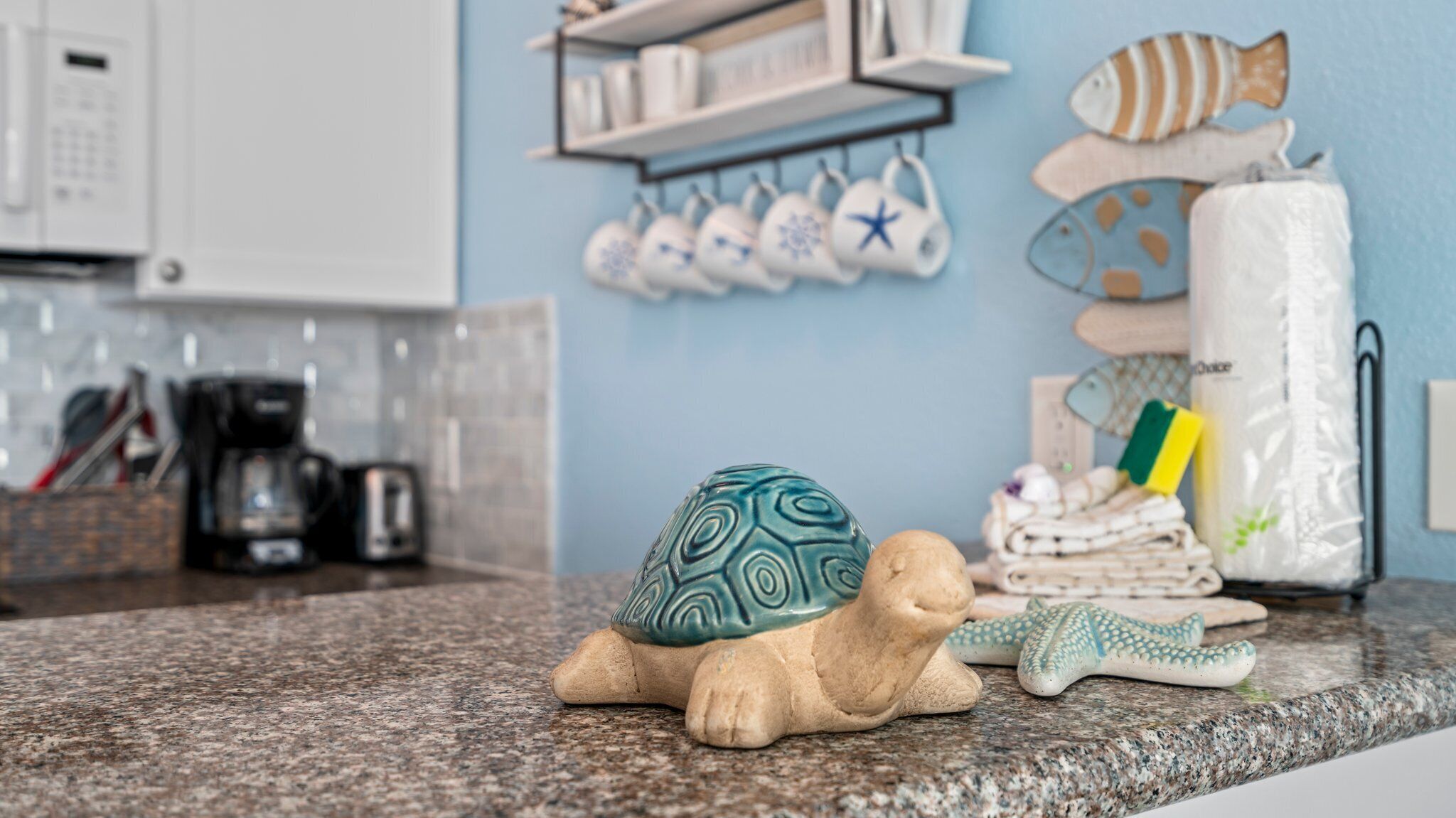 Un comptoir de cuisine orné d’une figurine de tortue en céramique, d’une étoile de mer et d’une pile de serviettes.