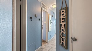 A hallway with a door labeled "BEACH" and a light fixture above it. - Salt Therapy, Great Amenities, Pool, Walk To Beach! (Galveston)