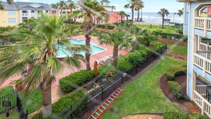 A resort with a pool, palm trees, and a view of the ocean. - Sea N Palms located at the award-winning Dawn Condominiums- 'Best of Galveston 2024' (Galveston)