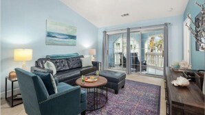 A living room with a sofa, armchairs, a coffee table, and a view through a glass door to the outside. - Sea N Palms located at the award-winning Dawn Condominiums- 'Best of Galveston 2024' (Galveston)
