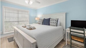 A bedroom with a bed, a ceiling fan, a TV, and a desk. - Sea N Palms located at the award-winning Dawn Condominiums- 'Best of Galveston 2024' (Galveston)