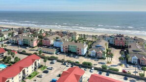 A coastal residential area with colorful houses, a beach, and a parking lot. - Ocean View Condo w/ resort amenities! (Galveston)