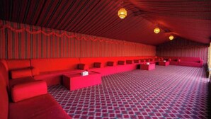 Une pièce aux couleurs dominantes rouges, avec un tapis à motifs, des canapés rouges et un plafond rayé.