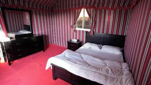 Une chambre à coucher avec un lit, une commode, une table de chevet et une fenêtre.