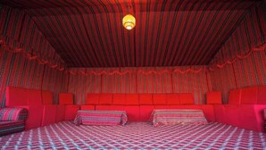 Une pièce avec un plafond à rayures rouges, un grand lit avec une literie à motifs et un canapé rouge.