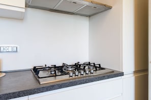 Une cuisine équipée d’une cuisinière à gaz, d’un plan de travail et d’une prise électrique murale.