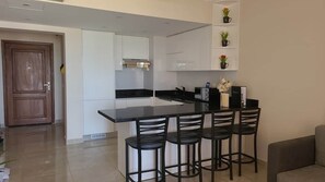 A modern kitchen with a bar area, white cabinetry, and a black countertop. - Breathtaking sea view – quiet *Susi's The View* (Hurghada 1,)