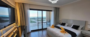 A hotel room with a bed, a TV, a desk, and a view of the outdoors.