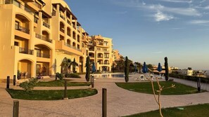 A hotel with multiple balconies, a swimming pool, and outdoor seating areas.