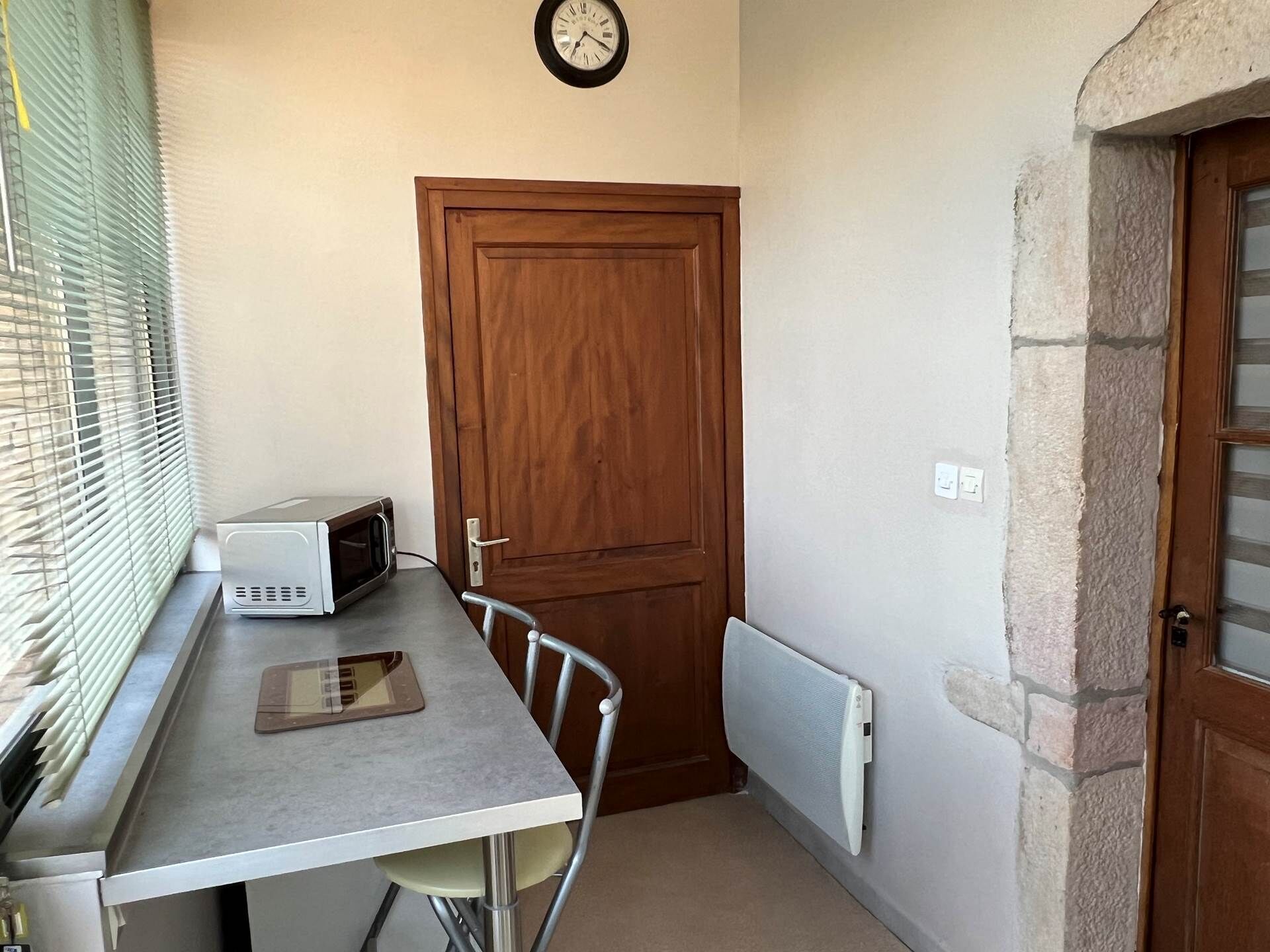 A small kitchenette with a microwave, a tablet, and a window with blinds.