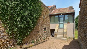 A stone building with a small entrance and a wooden staircase leading to a door. - My little paradise / private indoor pool (Lournand)