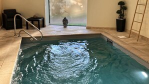 A swimming pool with a Buddha statue, a ladder, and a small table with a vase. - My little paradise / private indoor pool (Lournand)